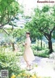 A woman in a yellow dress walking through a garden.