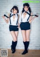 Two young women dressed in school uniforms posing for a picture.