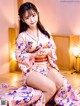 A woman in a pink kimono sitting on a bed.