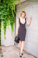 A woman in a black and white striped dress leaning against a garage door.