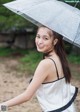 A woman in a white dress holding an umbrella.