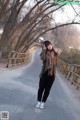 A woman standing on the side of a road in the middle of a forest.