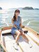 A woman in a blue and white striped dress sitting on a boat.