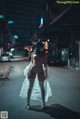 A woman in a white dress and a gas mask is walking down the street.