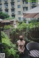 A naked woman sitting on a wooden deck next to a chair.