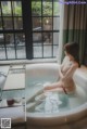 A naked woman sitting in a bathtub in a bathroom.