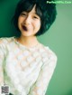 A woman in a white polka dot shirt smiles at the camera.