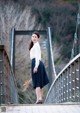 A woman standing on a bridge holding a bouquet of flowers.